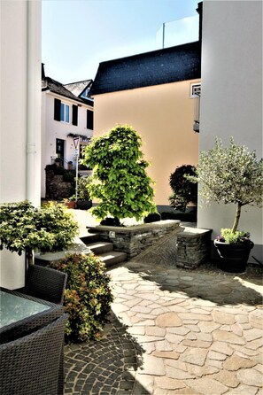 A courtyard with stone flooring, potted plants, and wicker furniture. - Feriendomizil am Lindenplatz (Bullay)