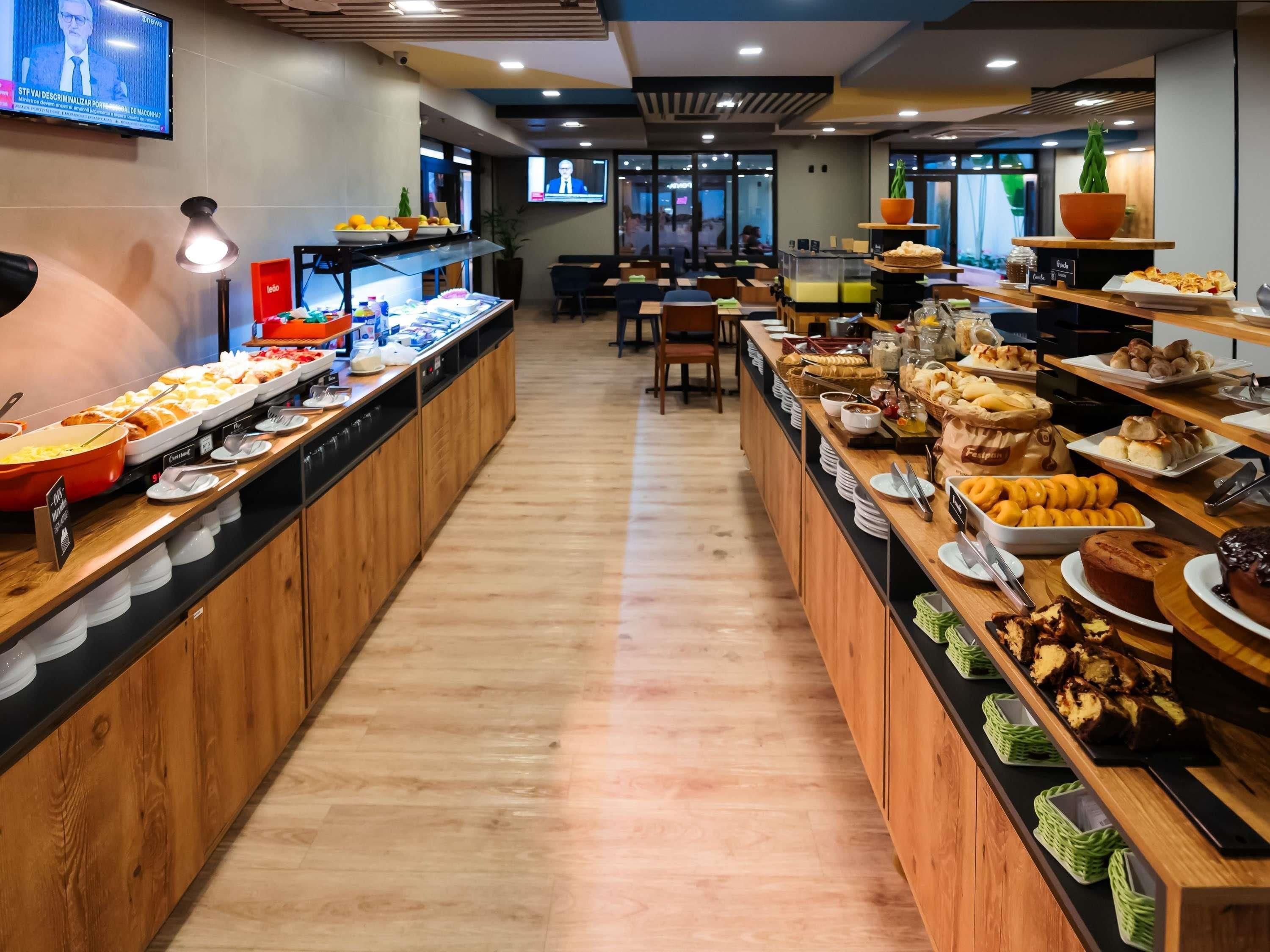 Zona de bufé con diferentes opciones de comida y una pantalla de televisión mostrando un noticiero.