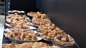 A buffet table with various baked goods including bread, pastries, and rolls. - Ibis Styles RJ Botafogo (Rio de Janeiro)