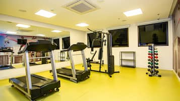A gym with treadmills, weight machines, and a rack of dumbbells.