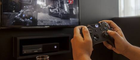 A person holding a game controller in front of a television displaying a video game scene.