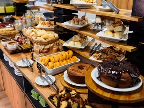 Un bufé con diversos productos de panadería y postres.