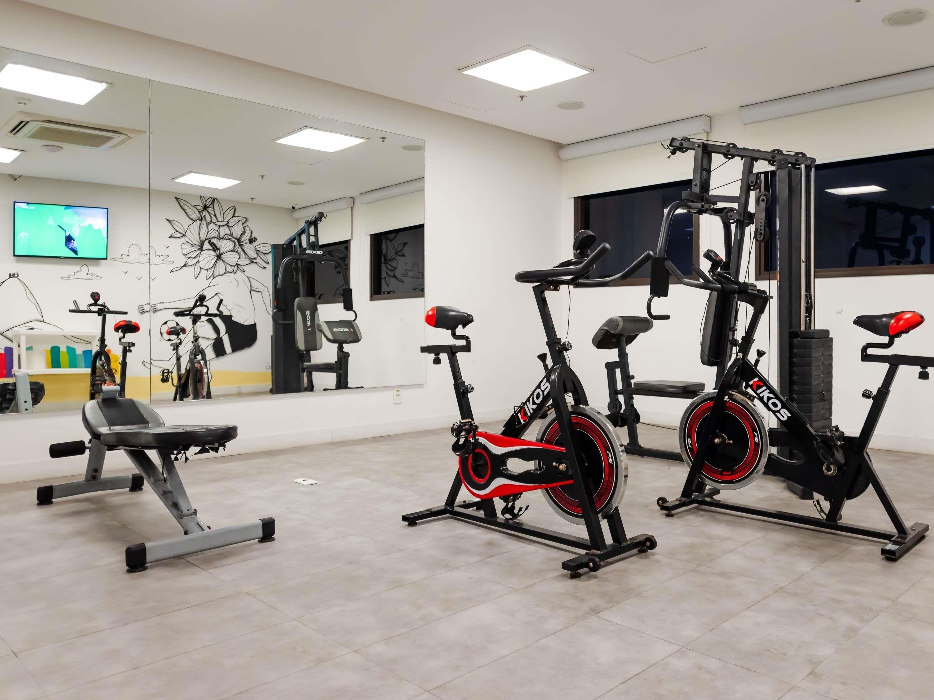 A gym with exercise equipment, a TV, and a mirror.