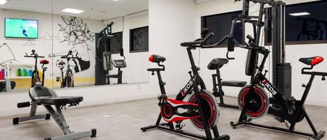 A gym with exercise equipment, a TV, and a mirror.