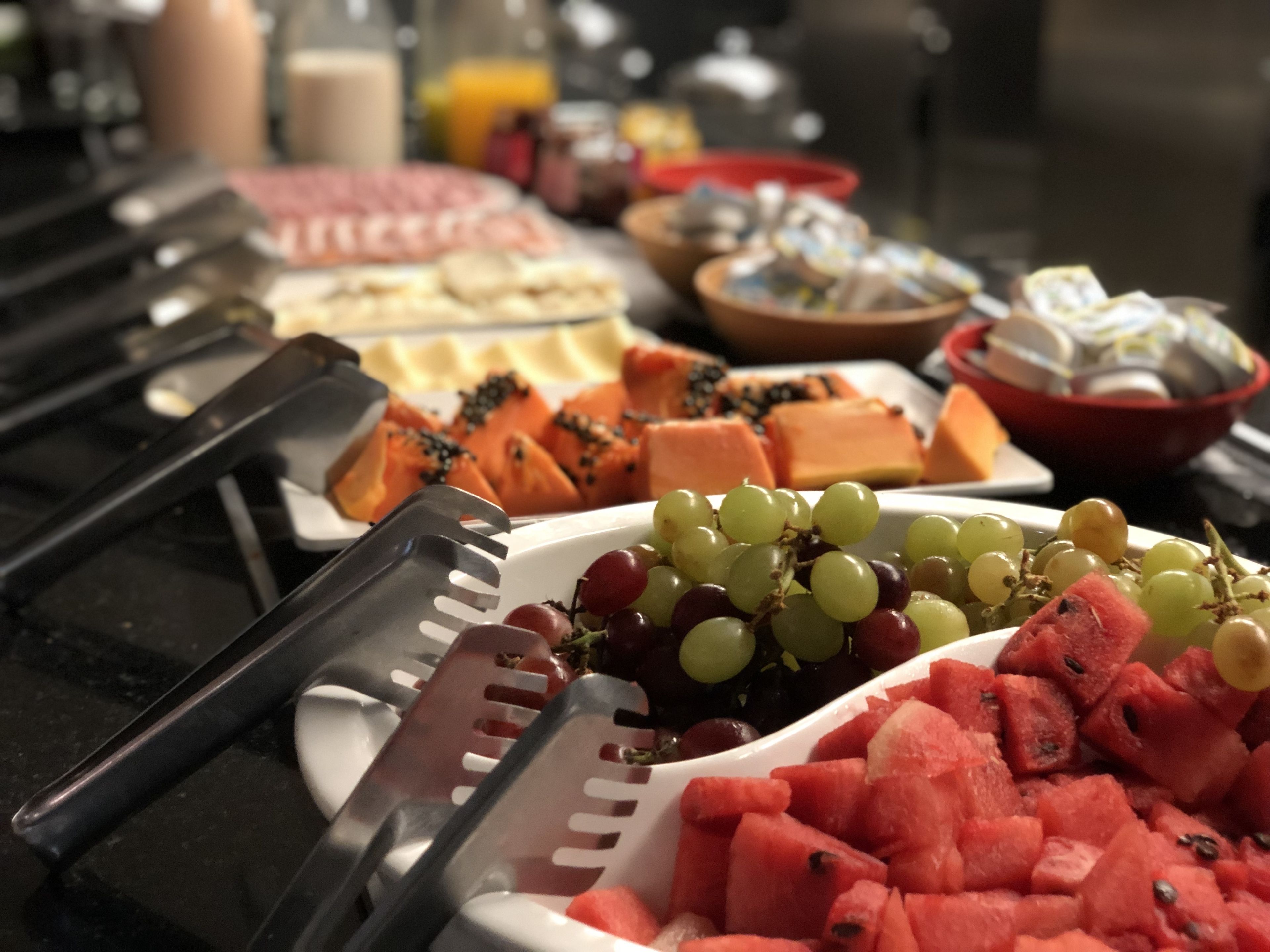 A buffet with various food items including watermelon, grapes, and cheese.