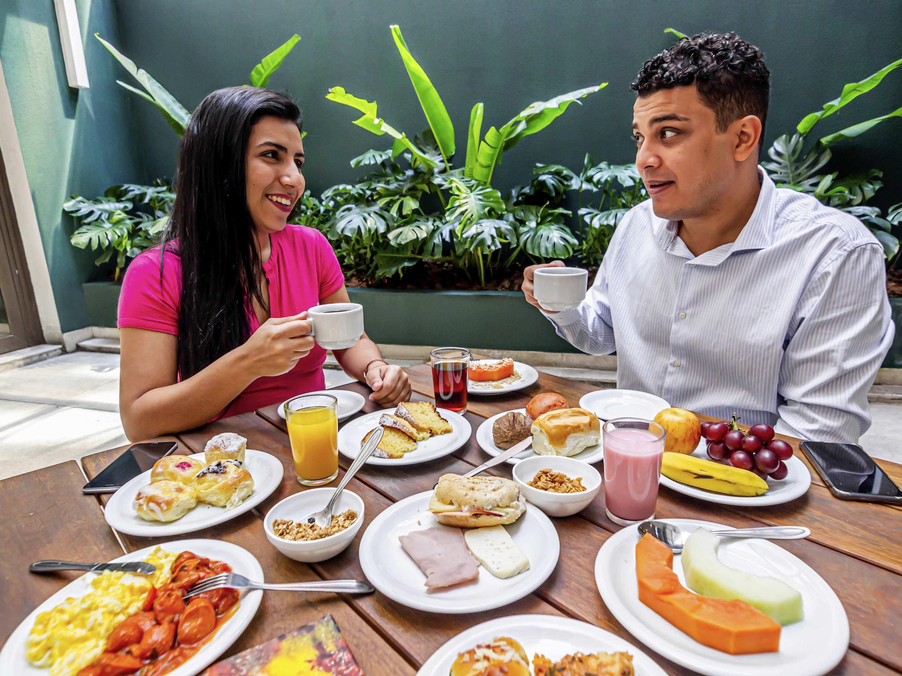 Uma mesa de jantar com diversos itens de café da manhã, incluindo ovos, torradas e frutas.