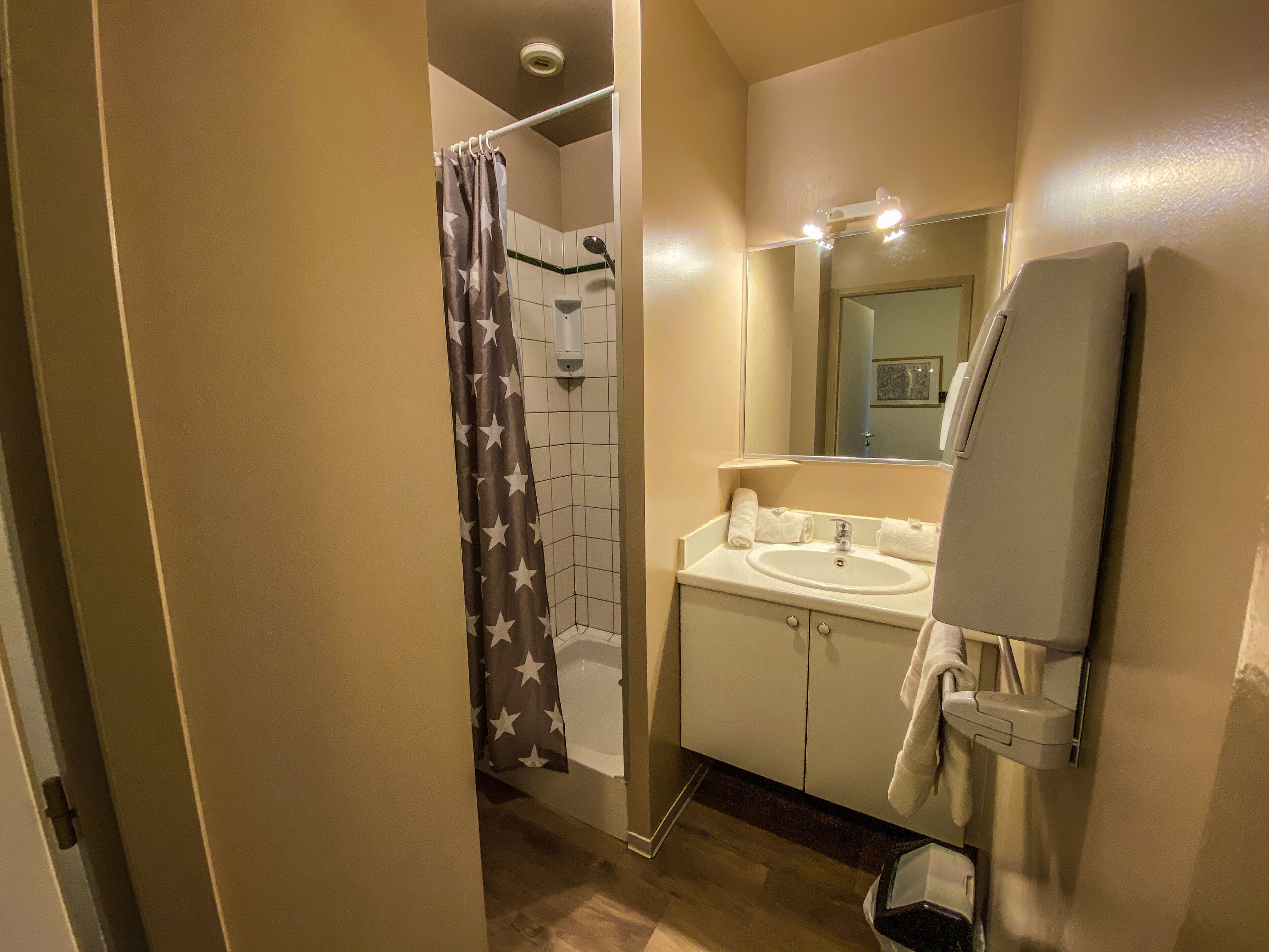A bathroom with a shower, a sink, and a mirror.