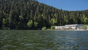 Un hotel junto al lago, con una ladera boscosa de fondo.