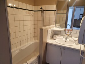 Un baño con azulejos blancos, una bañera, un lavabo y un espejo.
