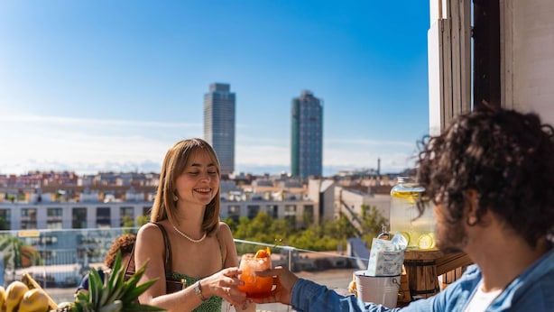 Una persona sosteniendo una bebida en un bar, con vista a la ciudad.
