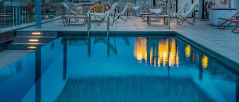 A rooftop pool area with lounge chairs and a bar.
