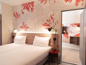 A hotel room with a bed, bedside lamps, a nightstand, and a wall with a coral reef pattern. - ibis Styles Barcelona City Bogatell (Barcelona)