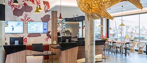 Un vestíbulo de hotel moderno con una recepción, computadoras y una lámpara colgante grande y llamativa.
