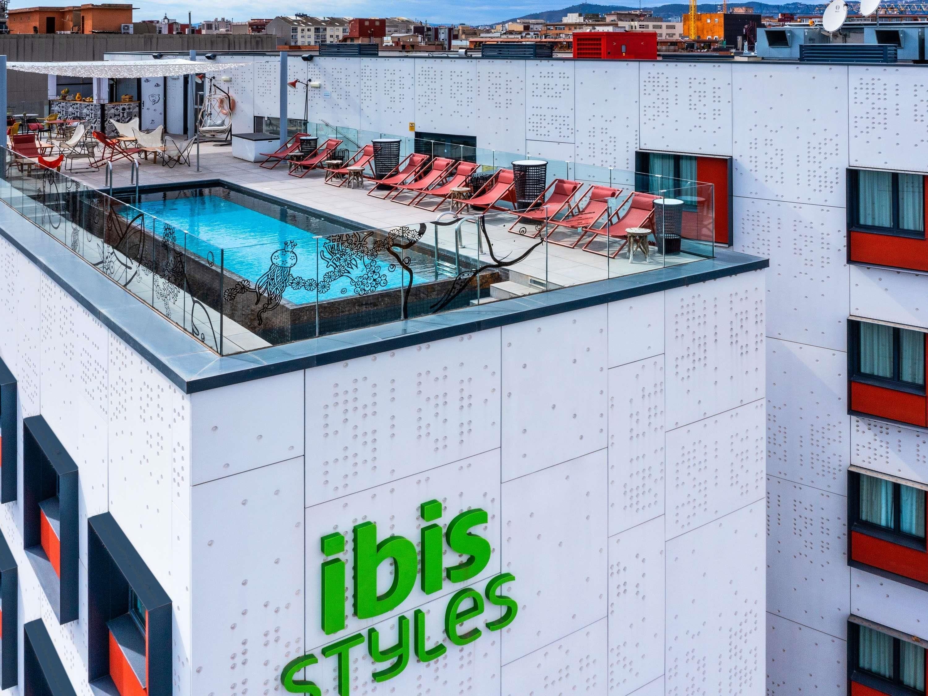 A rooftop pool area with lounge chairs and a sign reading 'ibis Styles'.