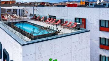 A rooftop pool area with lounge chairs and a sign reading 'ibis Styles'.