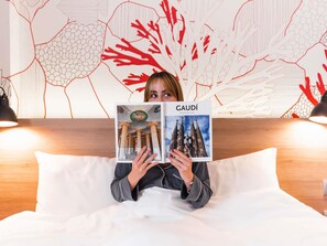En person holder en bog med titlen 'GAUDÍ', der viser billeder af arkitektoniske bygninger.