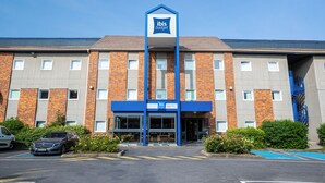 A hotel with a prominent 'ibis budget' sign, a brick facade, and a parking area with a blue parking space.