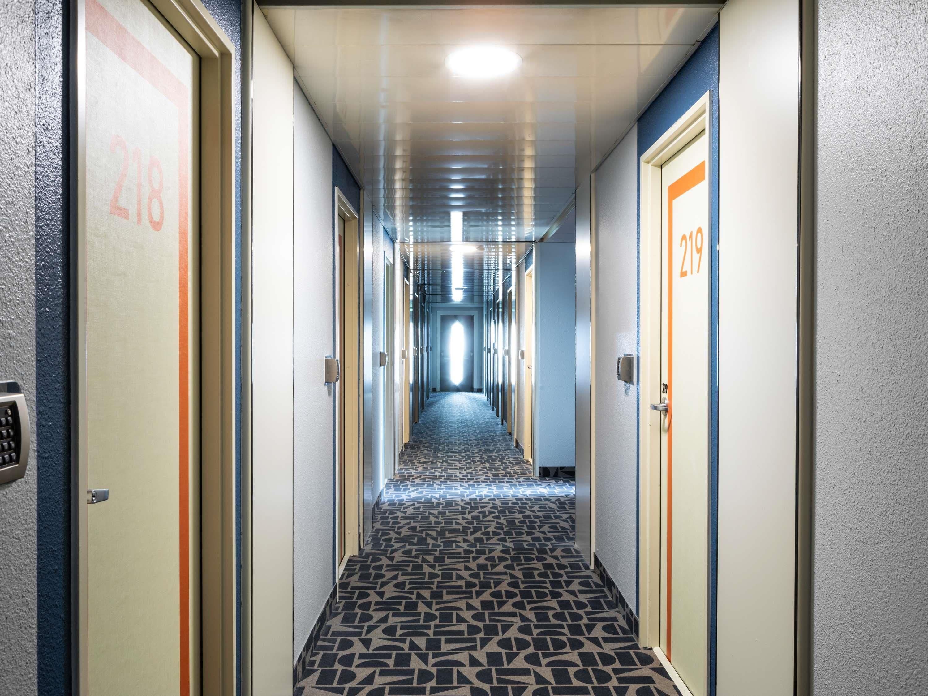 Un couloir d’hôtel avec des portes numérotées 218 et 219, donnant accès aux chambres.