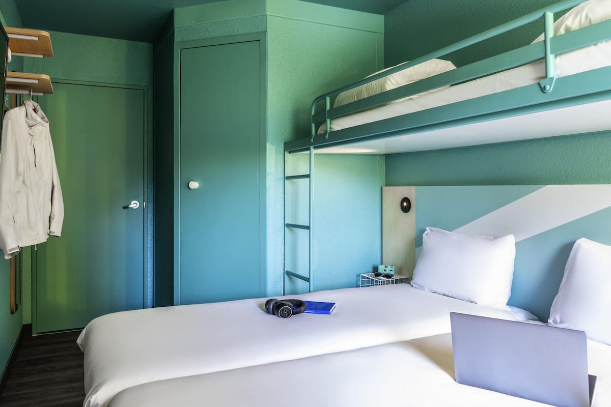Une chambre avec un lit superposé, un bureau, un ordinateur portable et un livre.