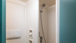 Une salle de bain équipée d’une douche, d’un porte-rouleau de papier toilette et d’un interrupteur.