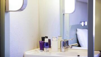 Une salle de bain équipée d’un lavabo, d’un miroir et d’articles de toilette.