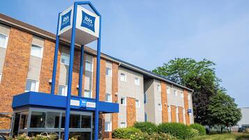 A hotel with a blue and white sign, brick facade, and a parking area.