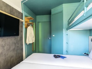 A compact room with a bed, a TV mounted on the wall, a coat rack, and a door. - ibis budget Marne la Vallee Chelles (Chelles)