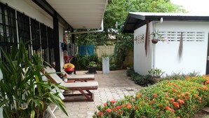Un patio con sillones de descanso, una planta en maceta y un parterre de flores.