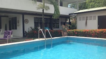 Relax by the pool surrounded by lush greenery and a seating area.