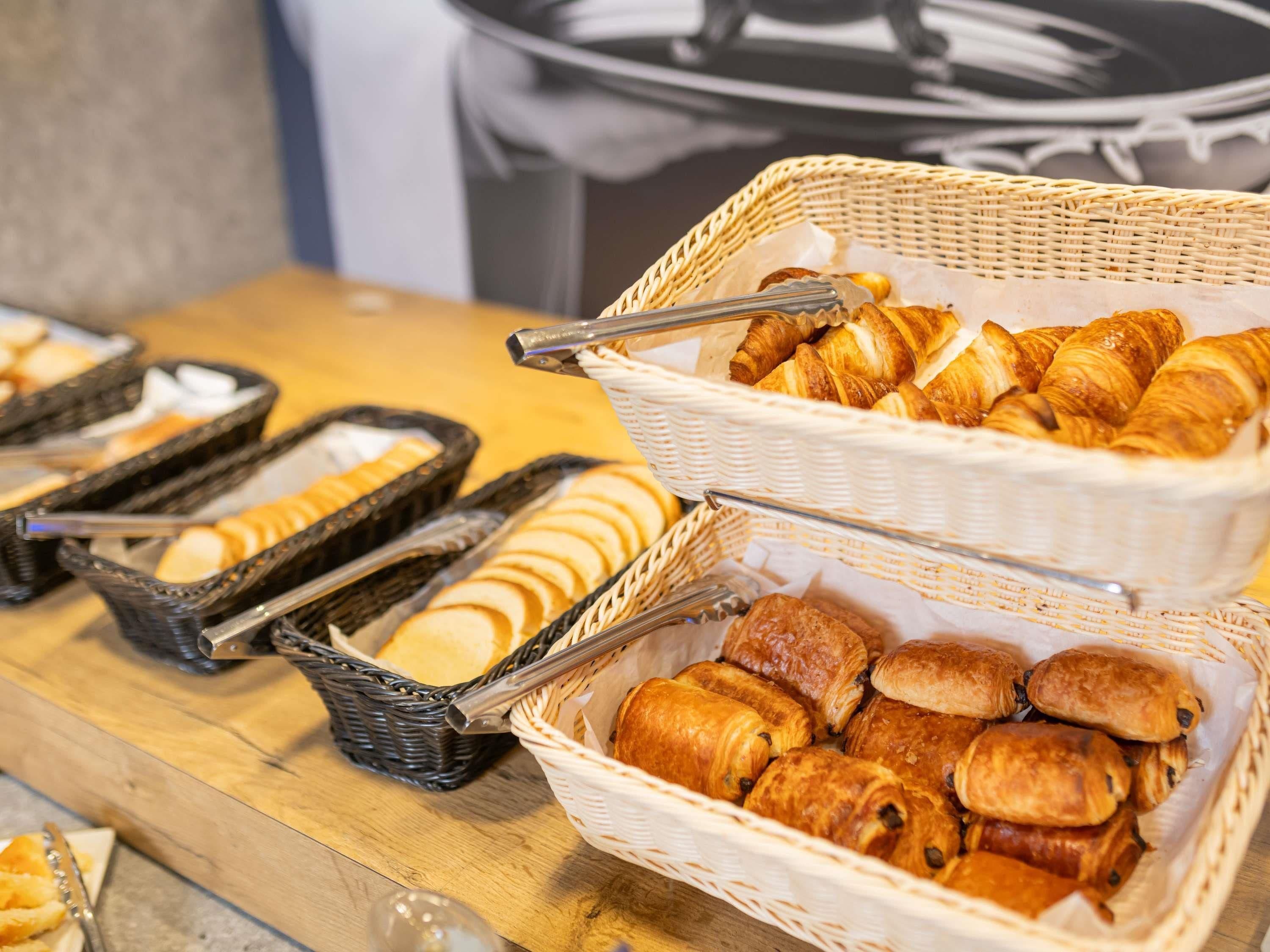 Uma mesa de buffet com diversos pães e pastelaria, incluindo croissants e pães.