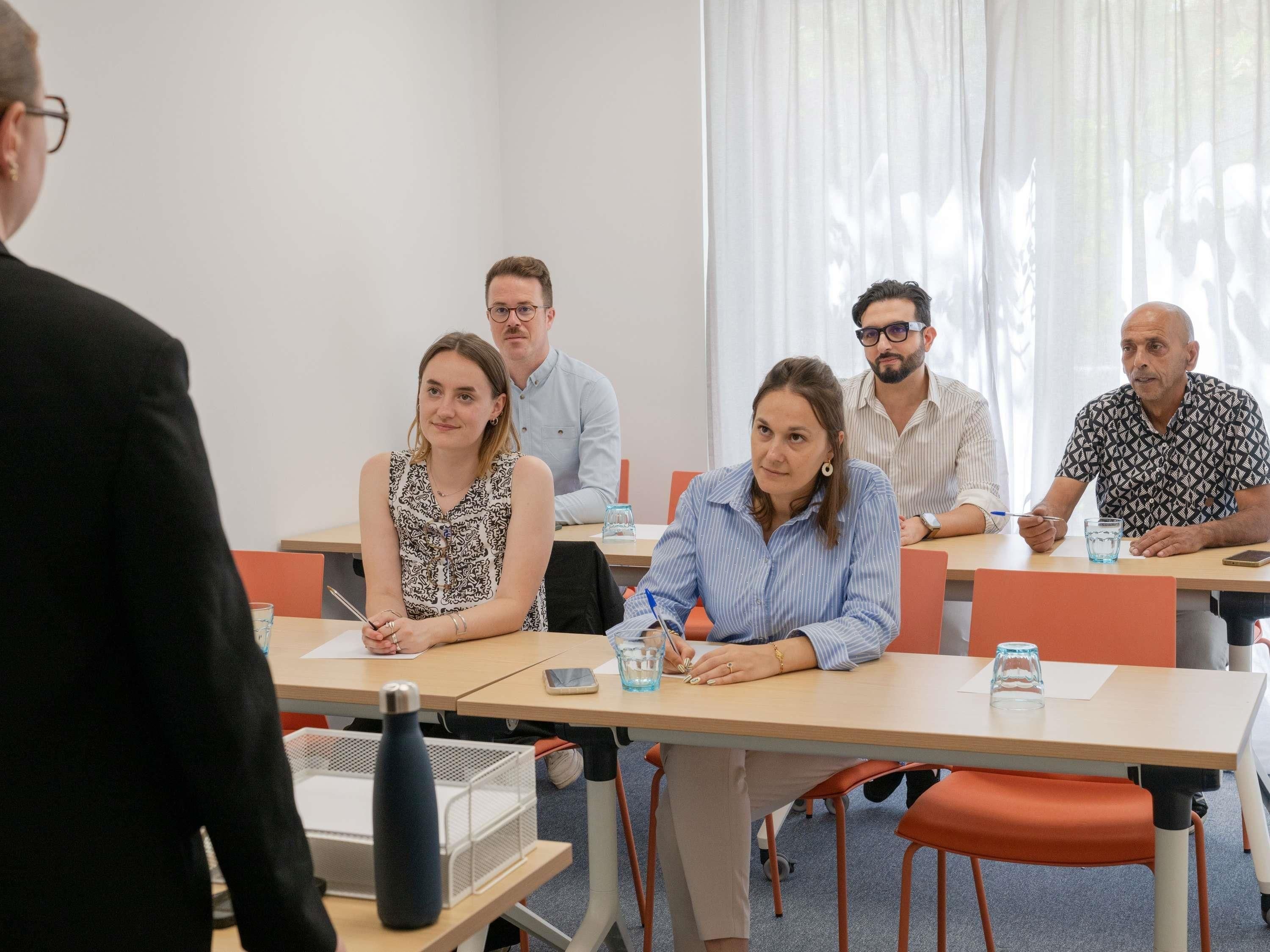 Un salón de conferencias con una mesa larga, sillas y una pizarra.