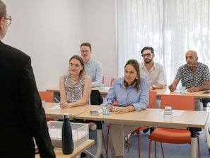Un salón de conferencias con una mesa larga, sillas y una pizarra.