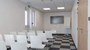 Un salón de conferencias con sillas blancas, una pantalla grande y piso a cuadros.