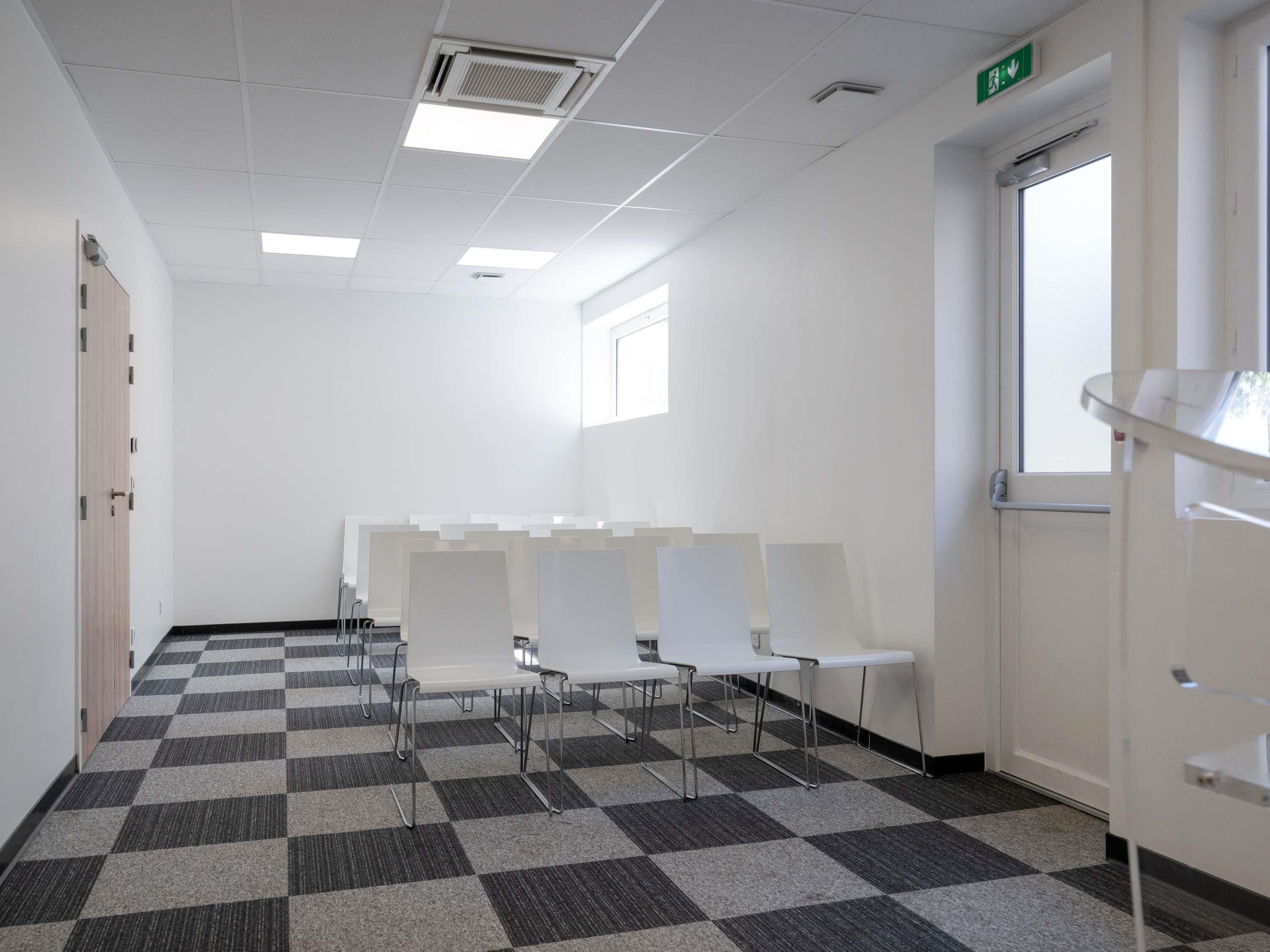 A room with a checkered floor, white walls, and a door with an emergency exit sign.