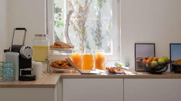 A breakfast setup with croissants, juice, and a fruit bowl on a kitchen counter.