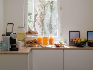 A breakfast setup with croissants, juice, and a fruit bowl on a kitchen counter. - ibis budget Lyon Caluire Cite Internationale (Caluire-et-Cuire)