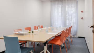 A conference room with a long table, chairs, a water pitcher, and a small plant.