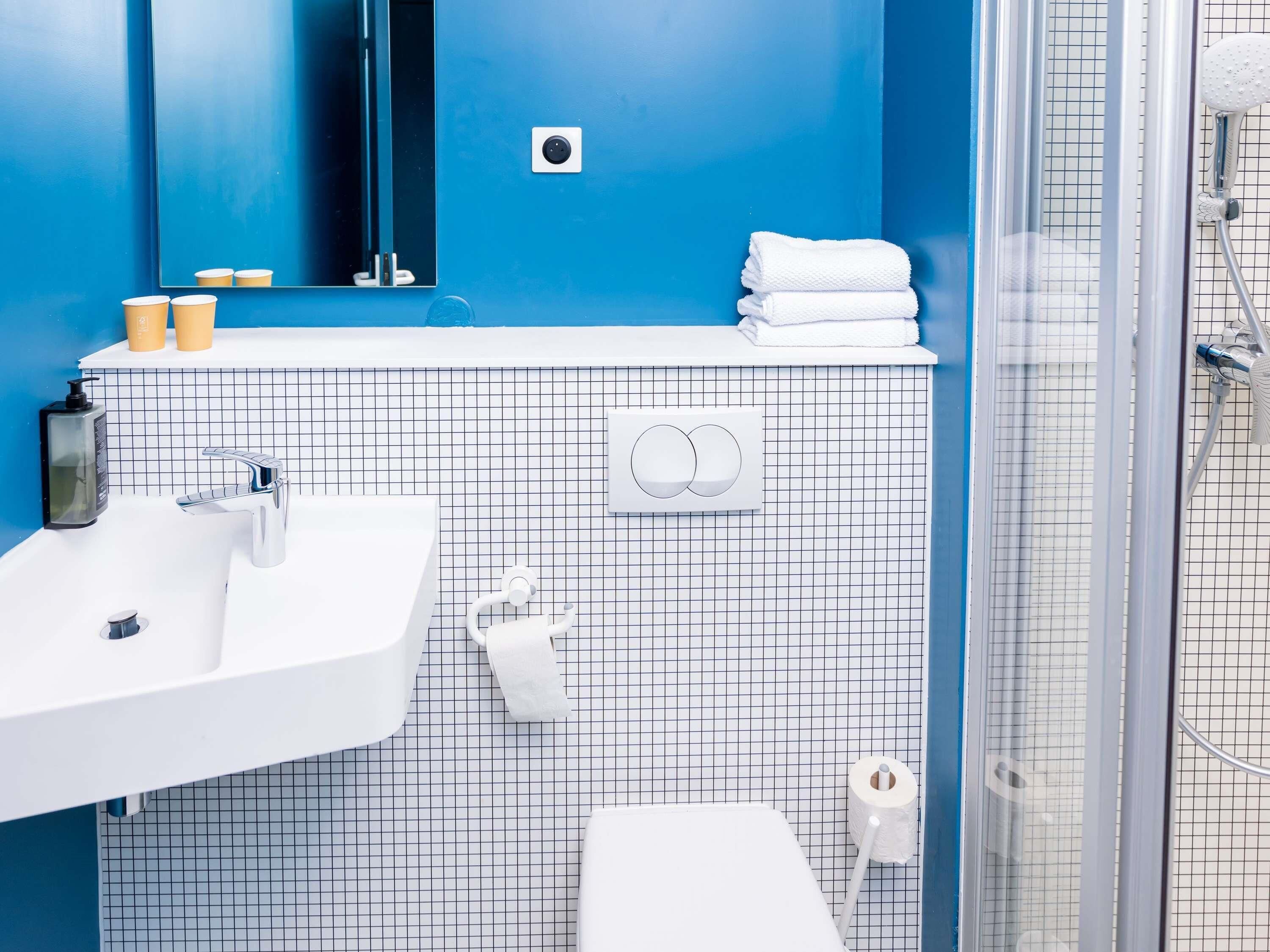 A bathroom with a white sink, a mirror, a towel rack, and a shower area.