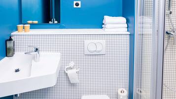 A bathroom with a white sink, a mirror, a towel rack, and a shower area.