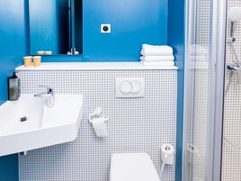A bathroom with a white sink, a mirror, a towel rack, and a shower area.