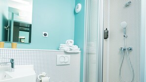 A modern bathroom with a glass-enclosed shower, a white sink, and a toilet. - ibis budget Lyon Caluire Cite Internationale (Caluire-et-Cuire)