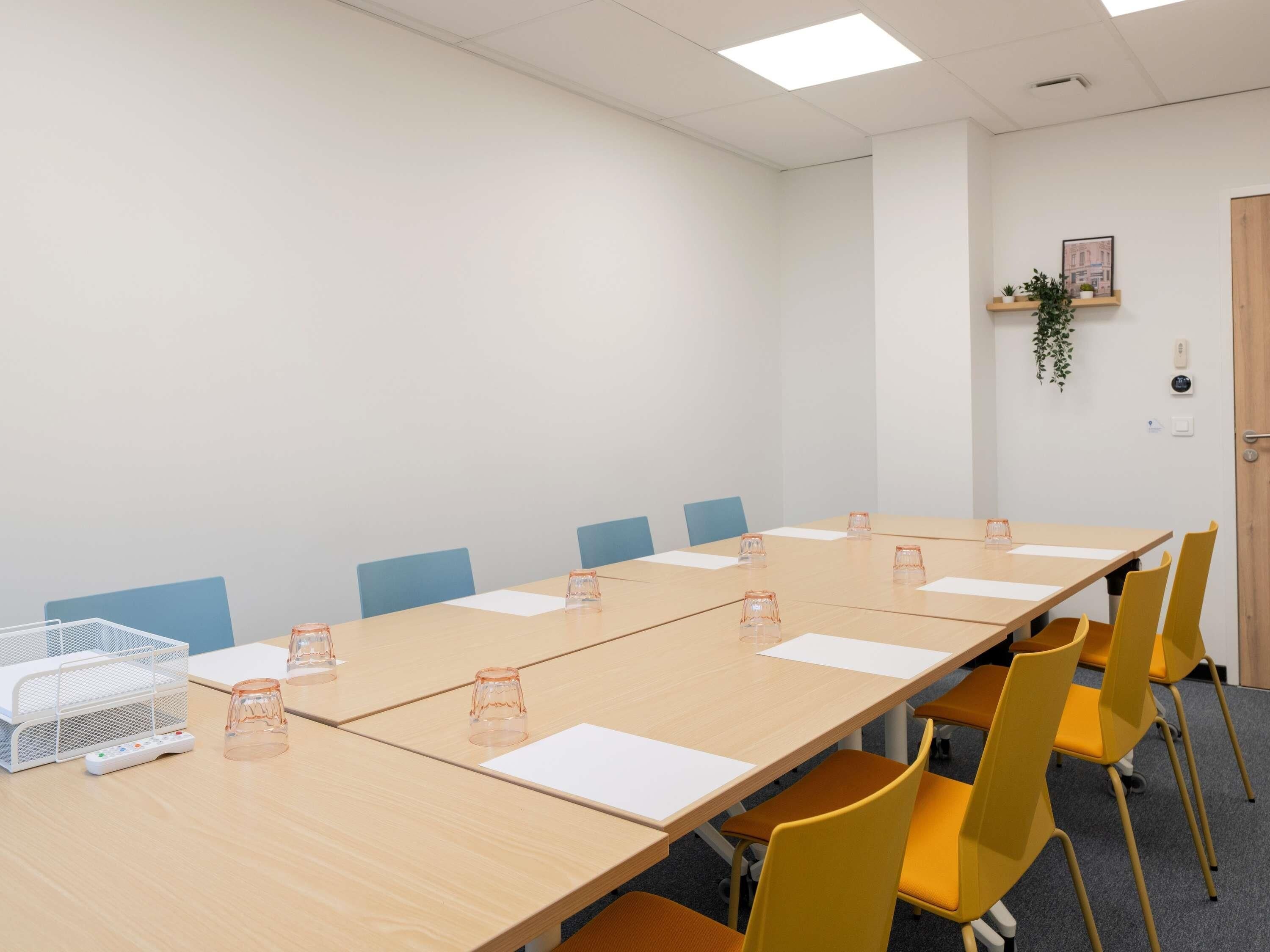 A conference room with a long table, yellow chairs, and a whiteboard.