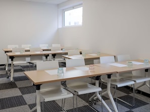 A conference room with multiple tables and chairs, equipped with water bottles and papers. - ibis budget Lyon Caluire Cite Internationale (Caluire-et-Cuire)