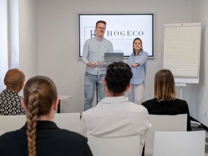 A presentation in a conference room with a projector screen displaying 'HOGEOCO' and 'SALLE DE SEMINAR'. - ibis budget Lyon Caluire Cite Internationale (Caluire-et-Cuire)