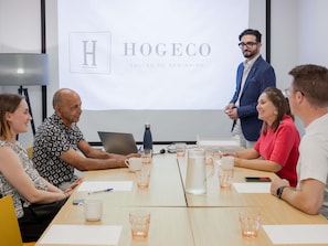 A meeting room with a projector screen displaying 'HOGECO SALLES DE SEMINAIRE'. - ibis budget Lyon Caluire Cite Internationale (Caluire-et-Cuire)