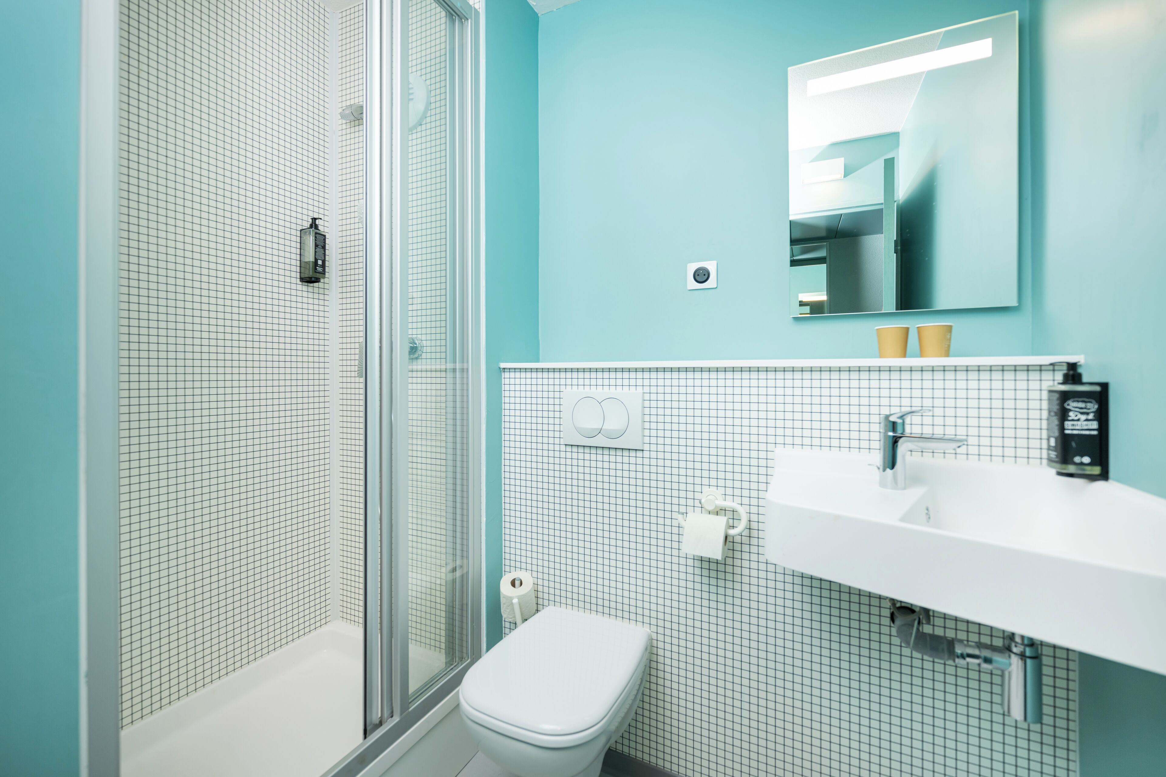 A bathroom with a shower, toilet, sink, and a mirror.