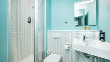 A bathroom with a shower, toilet, sink, and a mirror.