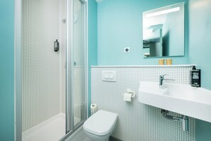 A bathroom with a shower, toilet, sink, and a mirror. - ibis budget Lyon Caluire Cite Internationale (Caluire-et-Cuire)