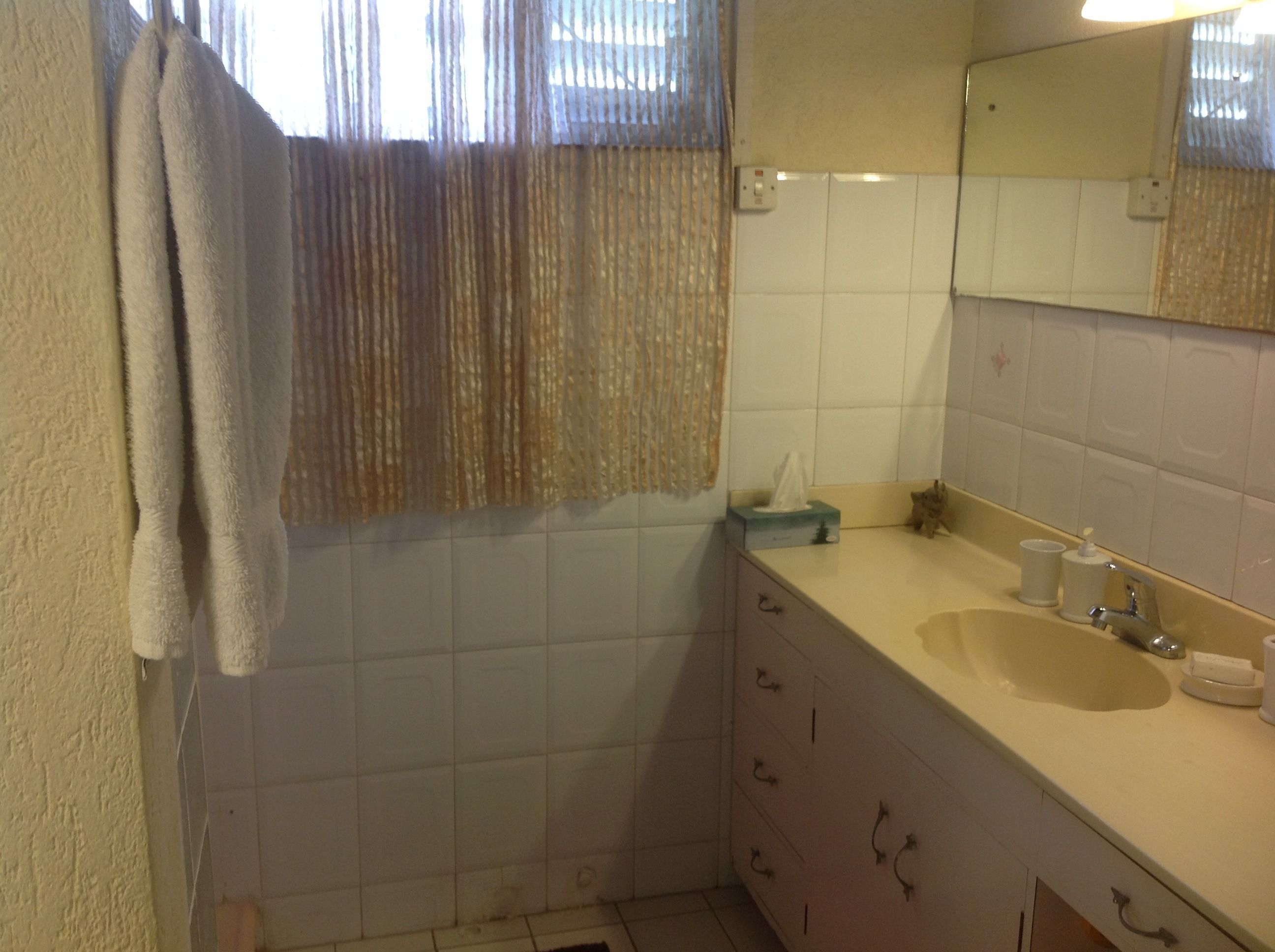 A bathroom with a white sink, a mirror, and a towel hanging on the wall.
