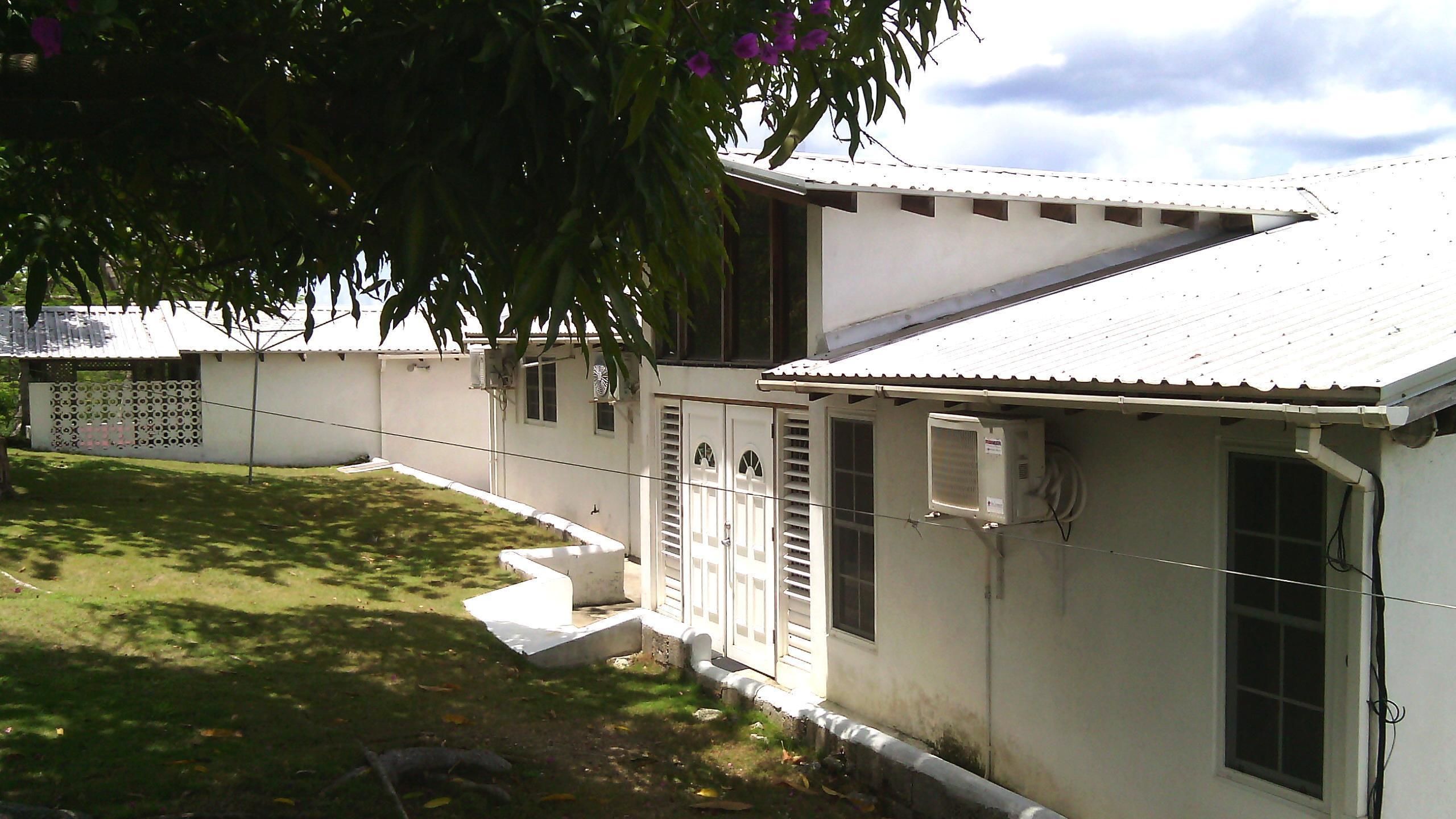Un bâtiment d’un seul étage, à l’extérieur blanc, doté d’un patio couvert et d’un petit jardin.
